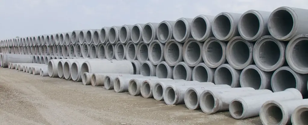 Tuyaux en béton empilés sur un chantier.